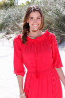 A brunette woman outside wearing a red dress