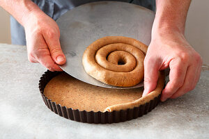 Linzertorte (nut and jam layer cake) being made: pastry edge being placed in a baking tin