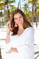 A brunette woman outside wearing a white blouse