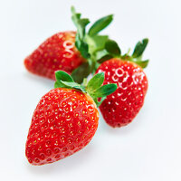Three strawberries in front of a white background