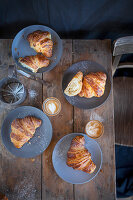 Croissants with cappuccinos on a rustic wooden table (top view)