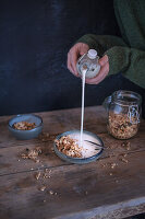 A person pouring milk into a bowl of muesli