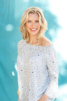 A young blonde woman wearing a blue-and-white stripped blouse