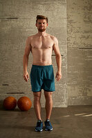 A young man standing upright in preparation for a strength exercise