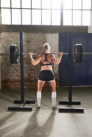A young woman lifting a barbell