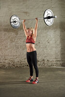 A young woman pressing a barbell