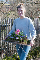 Woman carries board with hyacinths, crocuses and ray anemone