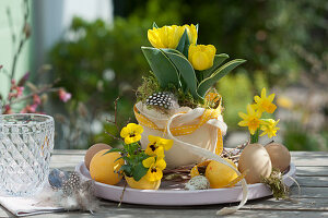 Easter table decoration with tulip and horn violets, Easter eggs and feathers