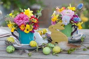 Small Easter table decoration with colourful bouquets in cups, Easter eggs and Easter bunny