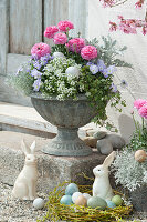 Flower spindle with spring flowers and wicker wreath as an Easter basket with Easter eggs and Easter bunnies