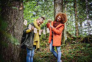 Girl and woman hanging up autumn garland in woods