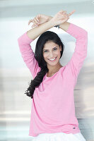 A dark-haired woman wearing a pink jumper