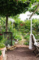 Blick in Garten mit Ziegelsteinweg, Kugelahorn und Sitzgruppe