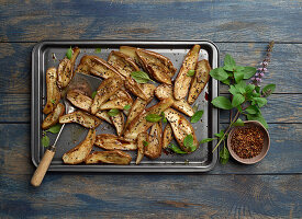 Roasted eggplant on baking sheet with spices and basil