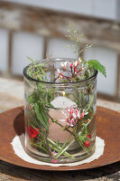 Candle lantern decorated with summery flowers, leaves and grasses