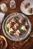 Prosciutto, arugula and goat cheese rollups on silver platter