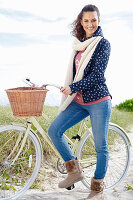 Junge Frau in Jeans, Sweatshirt, Kapuzenjacke und Pelzstiefeln an Fahrrad