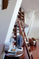 Bookcase with library ladder and fireplace in high-ceilinged room