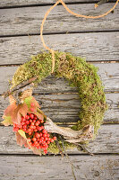Moss wreath with viburnum berries and twigs on weathered wood