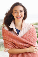 A young brunette woman wearing a light shirt blouse with a salmon pink woollen shawl