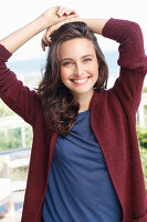 A young brunette woman wearing a blue t-shirt and a wine red cardigan