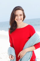 A young brunette woman wearing a red jumper with a grey woollen shawl