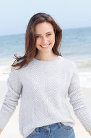 A young brunette woman wearing a light jumper and jeans