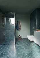 A shower cubicle in a bathroom with grey floor tiles