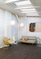 Armchair and sofa in a room with skylights and brick walls