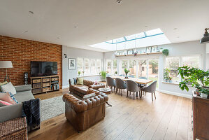 Offener Wohnraum mit Chesterfield-Sofa und Esstisch unterm Glasdach