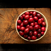 Cranberries in bowl on wooden cutting board