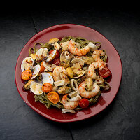 Mediteranian seafood, white wine, shrimp, mussels, clams, calamari, tomatoes in plate on black