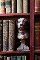 Antiquarian books and bust of dog on book shelves