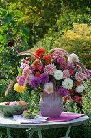 Bouquet of dahlias, zinnias and feather bristle grass, bowl with flowers in the water