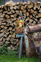 Bunte Frühlingsblumen und Blumenzwiebeln im Glasgefäß vor Holzlager