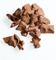 Schokolade in Stücken und Röllchen vor weißem Hintergrund
