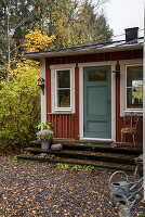 Falu-red Swedish house with blue-grey front door in autumnal garden