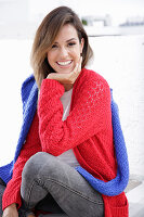 Junge Frau in rotem Strickpullover und blauer Pullover über den Schultern
