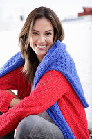 Junge Frau in rotem Strickpullover und blauer Pullover über den Schultern