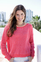 A young woman wearing a fuchsia jumper and white jeans