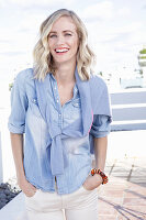 A blonde woman wearing a denim shirt with a jumper over her shoulders