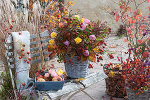 Herbststrauß aus Hagebutten und Rosen in Korbvase