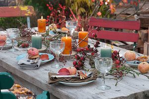 Autumn table decorations with rose hips, candles and apples