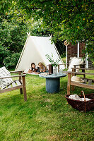 Two girls playing in tent in garden with seating area in foreground