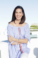 A brunette woman wearing a blue-and-white striped Carmen blouse