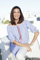 A brunette woman wearing a blue-and-white striped Carmen blouse