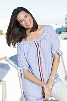 A brunette woman wearing a blue-and-white striped Carmen blouse