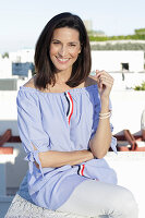 A brunette woman wearing a blue-and-white striped Carmen blouse