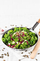 Winter salad with green kale, pomegranate seeds, peas, mozzarella and pumpkin seeds
