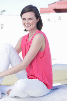 A young woman wearing a pink top and white white trousers